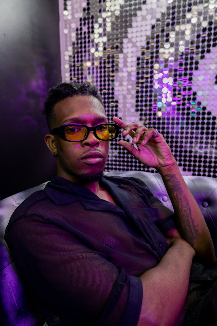 Crafting Captivating Headlines: Your awesome post title goes here Close-up portrait of a young African man in a black shirt and yellow glasses with a vibrant neon background.