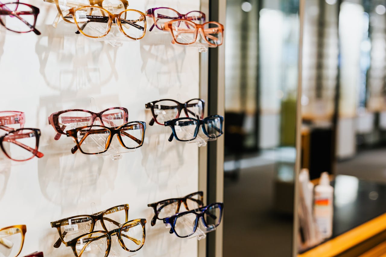 Offerings Assorted eyeglasses on a well-lit shelf in an optician's store.